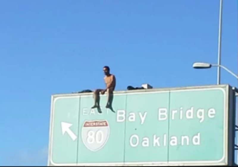 Naked guy sitting on I 80 freeway sign oakland