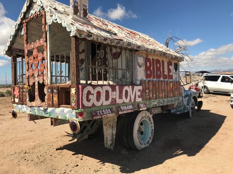 An old truck decorated with a ton of paint near Salvation Mountain