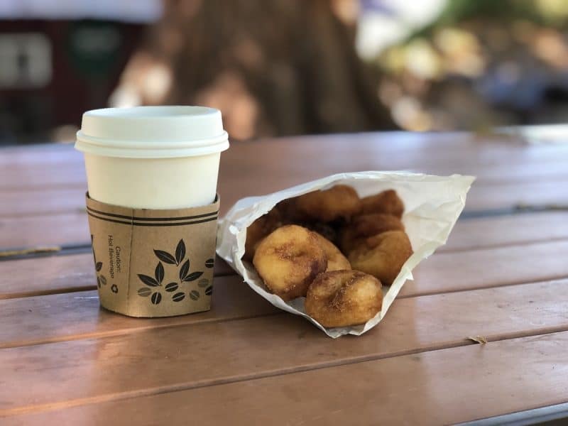 A bag of a dozen apple cider donuts and a cup of hot apple cider in Oak Glen California